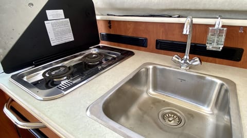 Kitchen features a sink with hot and cold water, 2-burner stove-top, and under counter refrigerator
