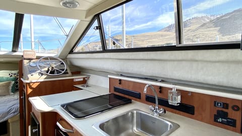 Kitchen looking toward the front of the boat, featuring a sink with hot and cold water, 2-burner stove-top, and under counter refrigerator