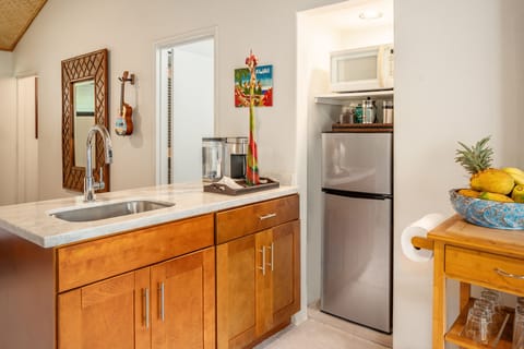 A kitchenette with quartz countertop, sink with disposal, microwave and coffee.