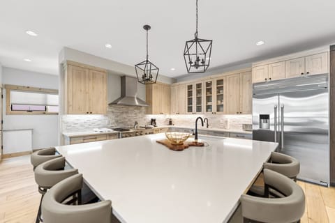 Full kitchen with stainless steel appliances, 2 sinks, and a large kitchen island with breakfast bar seating for casual dining.