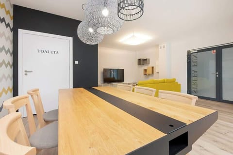 A bright dining space with a wooden table, black chairs, and modern lighting fixtures.