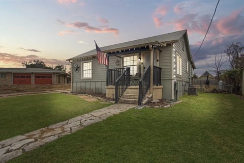 Charming cottage retreat with a welcoming front porch, glowing evening lights, and a peaceful yard-perfect for relaxing after a day of adventure.
