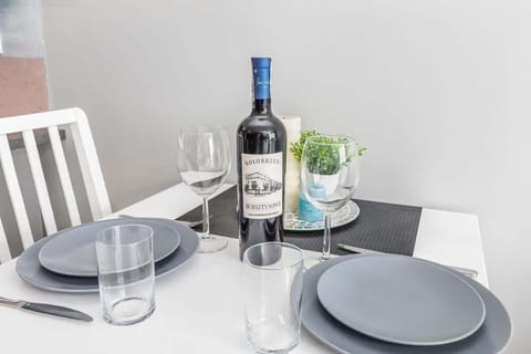 A close-up of a small dining table with plates, glasses, and a bottle of wine for a cozy meal.