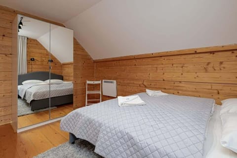  A cozy bedroom with wooden walls and ceilings, featuring a double bed and a wardrobe for a practical yet inviting design.