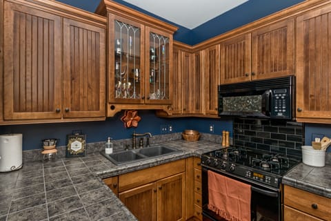 Stocked cabinets with dinnerware, cooking utensils, cutlery, and glassware.