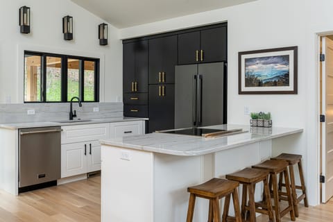 Sleek kitchen with breakfast bar seating for 4, a dishwasher & standard drip coffeemaker.