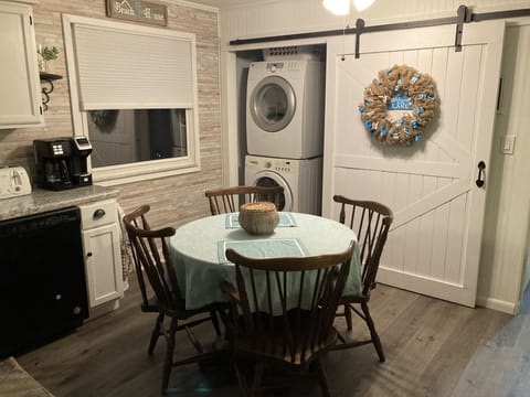 kitchen table with 4 chairs, sliding door with washer/dryer behind it.