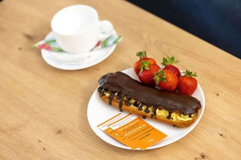 A close-up image of a breakfast spread on a wooden table, featuring a cup of coffee, strawberries, and a pastry, offering a cozy, homely feel to the apartment.