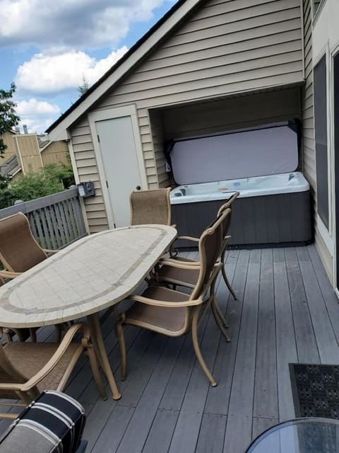 Private outdoor deck equipped with a hot tub, dining table and barbecue.
