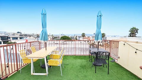 Soak up the sun on this expansive rooftop terrace, featuring lush artificial turf, seating, and multiple dining tables perfect for an open-air meal with a view.