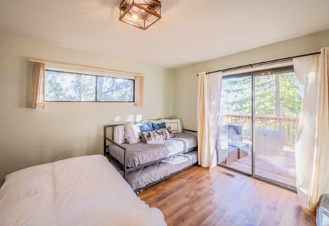 A light-filled bedroom featuring a plush bed and access to a sunny deck, promising relaxation in a serene cabin setting.