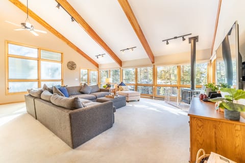 Main level living area with large flat screen TV, ample seating, vaulted ceilings and panoramic windows offering incredible views.