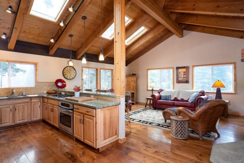 The open-concept living room flows into the kitchen, boasting high vaulted ceilings and stunning wood floors, offering a bright and spacious feel