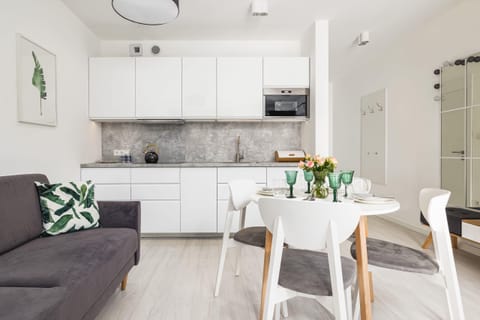 A sleek, open-plan kitchen adjacent to a dining table elegantly set with glassware and greenery.