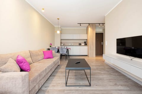A spacious living area with a gray sofa and a dining table, connected seamlessly to the kitchenette.