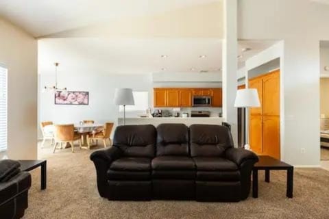 Living room facing kitchen and dining room with leather dual recliner couch.