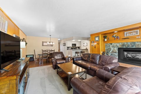 Living room with ample seating, wood burning fireplace, TV, and balcony access.