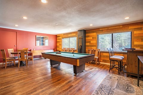 Game room with pool table, TV, bar area, and round table.