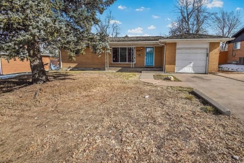 A cozy single-story brick home with a spacious driveway, attached garage, and a welcoming front entrance in a suburban neighborhood.