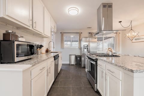 - Modern kitchen featuring granite countertops, sleek cabinetry, & a gas cooktop
- Fully equipped with stainless appliances, essentials, & a large sink with a pull down faucet
- Natural light & checkered curtains add charm to this highly functional s