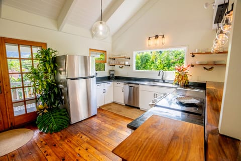 Stocked vaulted kitchen opens up to dining Lanai with massive waterfall views