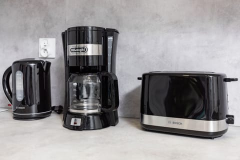 Glancing at the kitchen worktop on which stands a black electric kettle, coffee machine and toaster.