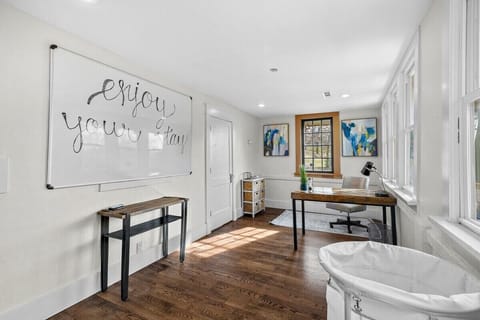 This room features a desk, swivel chair, large whiteboard, Samsung washer and dryer, laundry detergent, dryer sheets, rolling laundry bin and hooks to dry clothes.