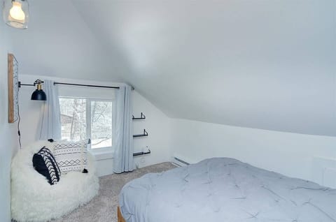 - Quiet corner bedroom with soft lighting, plush bedding, and sloped ceiling design
- Fuzzy accent chair with pillows makes a perfect nook for reading or lounging
- Snowy views through the window enhance the calm and cozy atmosphere