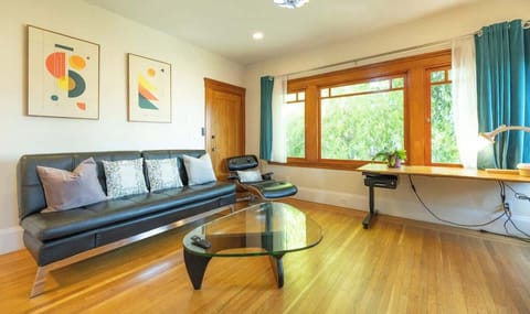 Unwind in this bright living area featuring a sleek sofa, modern artwork, and large windows that fill the space with beautiful natural light
