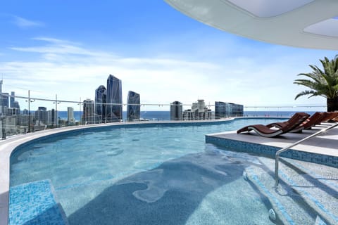 Communal rooftop pool with sun loungers and a view of the skyline