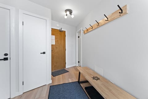 Unit entryway with mounted hooks and storage closet.