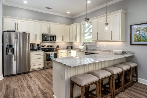 Cook with ease in a fully equipped kitchen featuring stainless steel appliances, granite countertops, and a breakfast bar with seating for four