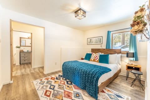 Lower level guest bedroom one with queen size bed, en suite bathroom, walk-in closet and hardwood flooring.