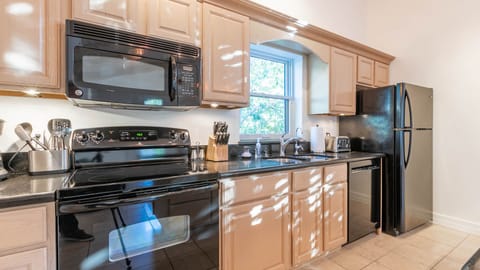 Compact guest kitchen with full appliances, ample storage, and bright décor