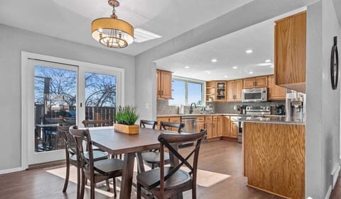 - Bright dining area with a wood table, black chairs, & contemporary chandelier
- Sliding doors let in natural light & offer access to the deck for indoor outdoor meals
- Open to the kitchen, it’s perfect for family dinners or casual brunches at home
