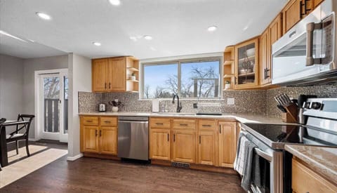- Enjoy garden views while prepping meals at the large window above the sink area
- Natural light fills this bright kitchen with stainless appliances & wooden cabinetry
- Backsplash tiles add visual texture while countertops offer extra of prep space