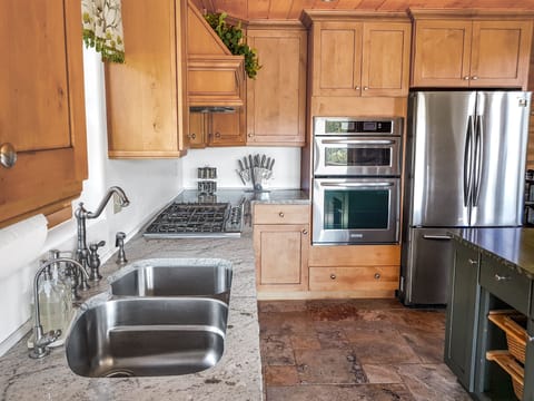 A large gas range with six burners, microwave (above the oven), oven and fridge.