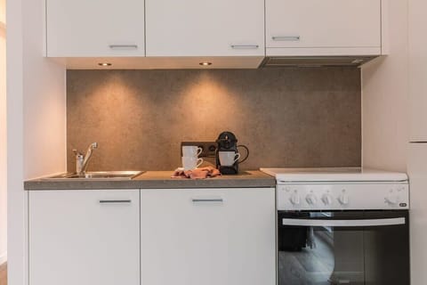 Fully equipped kitchen with modern appliances, including a stove, oven, and coffee maker. The sleek white cabinetry provides plenty of storage, while the clean countertops offer ample space for meal prep. Perfect for preparing home-cooked meals durin