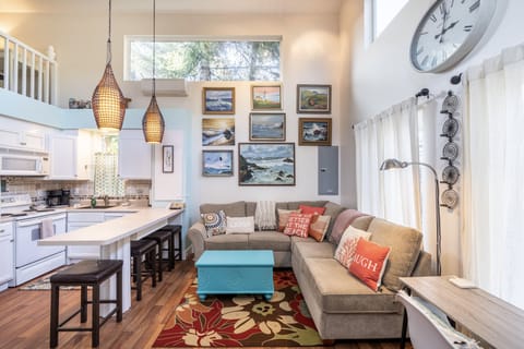 Living area and gallery of sea-inspired art and desk with view of front yard.
