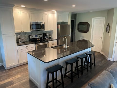 Beautifully remodeled kitchen w/white cabinets, pantry, granite bar & deep sink