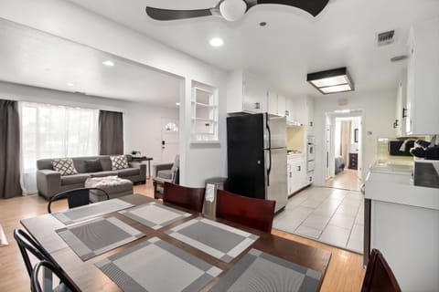 "Elegant dining area with seating for six, featuring a modern ceiling fan and large wall art of a waterfall. French doors bring in natural light, adding to the room's inviting ambiance."