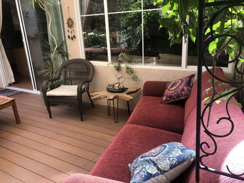 Outside living space includes a couch, teak patio table and feels like an oasis