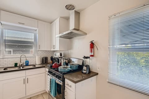 Enjoy the full kitchen with a refrigerator, oven, stove, microwave, coffee, creamers, mixers, spices, pots, pans, cooking supplies, cutlery, cups, plates, bowls, utensils, small appliances, view of the backyard, and many more essentials.