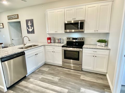 Open kitchen has full-sized stainless steel appliances and granite counters 