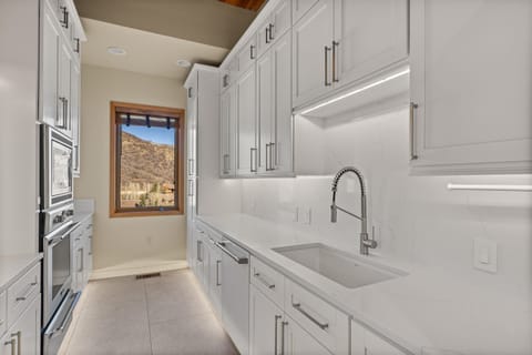 Step into your culinary sanctuary with pristine white cabinetry, gleaming quartz countertops, and professional-grade appliances. The mountain views through your window make cooking feel like a retreat.