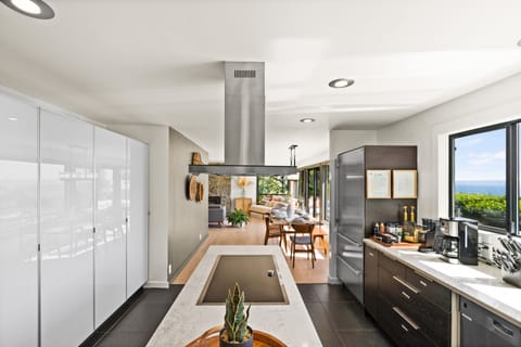 Fully stocked modern kitchen with induction stove top, double oven, coffee bar.