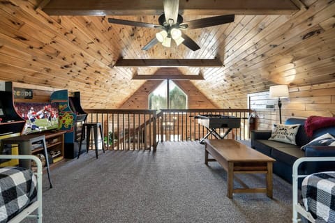 Loft area with arcade games, board games, foosball, sitting area, smart roku tv,  and two full size beds