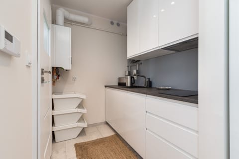 A compact kitchen featuring white cabinetry, integrated appliances, and a clean, modern design.