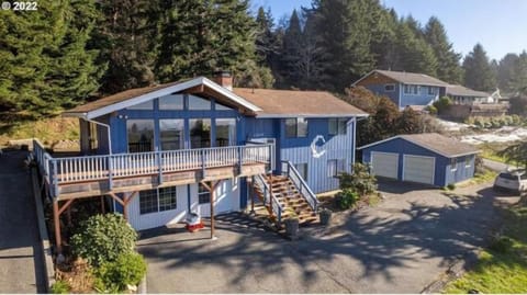 Coastal home framed by trees, steps from shimmering blue water.