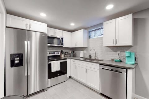 Bright kitchen with pots, pans, spices, and stainless appliances.